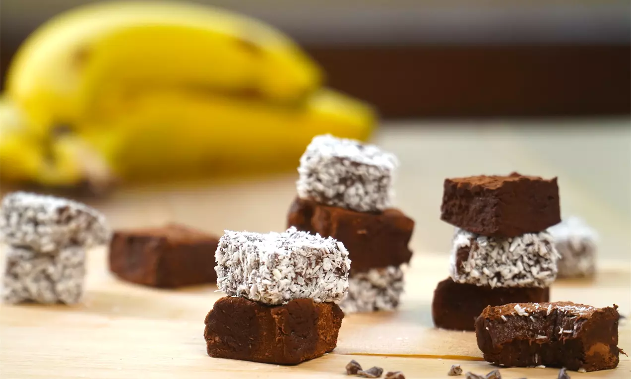Bananinha zero açúcar com cacau em prato rústico, palitos de banana cobertos por cacau escuro, polvilhados e decorados com folhas de hortelã